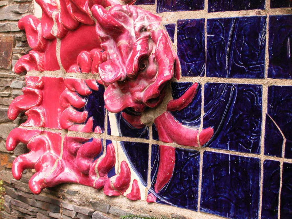 Close up of the red dragon Wyrm head from a monumental 4 x 8 foot ceramic stoneware bas relief mural, glazed in deep crimson and cemented into Catskill Mountain bluestone, projecting outward in three dimensions.