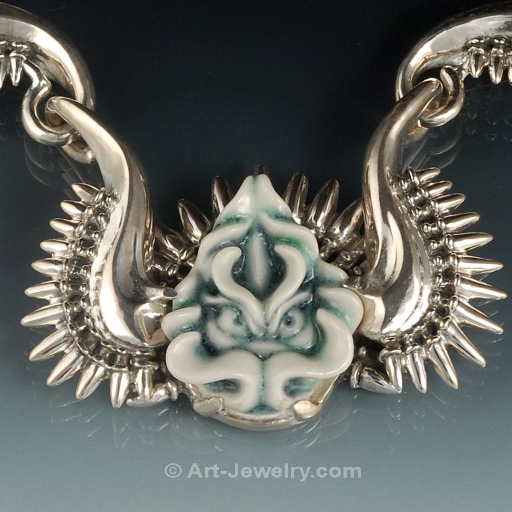 Close‑Up of Hand‑Carved Porcelain Dragon Face in Sterling Silver Setting Close‑up of hand‑carved porcelain dragon face set in sculpted sterling silver bezel, unique fine art dragon jewelry.