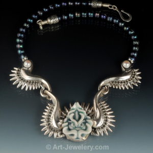 Handcrafted porcelain dragon face set in artist‑carved sterling silver wings with black pearl, one‑of‑a‑kind fine art dragon necklace.