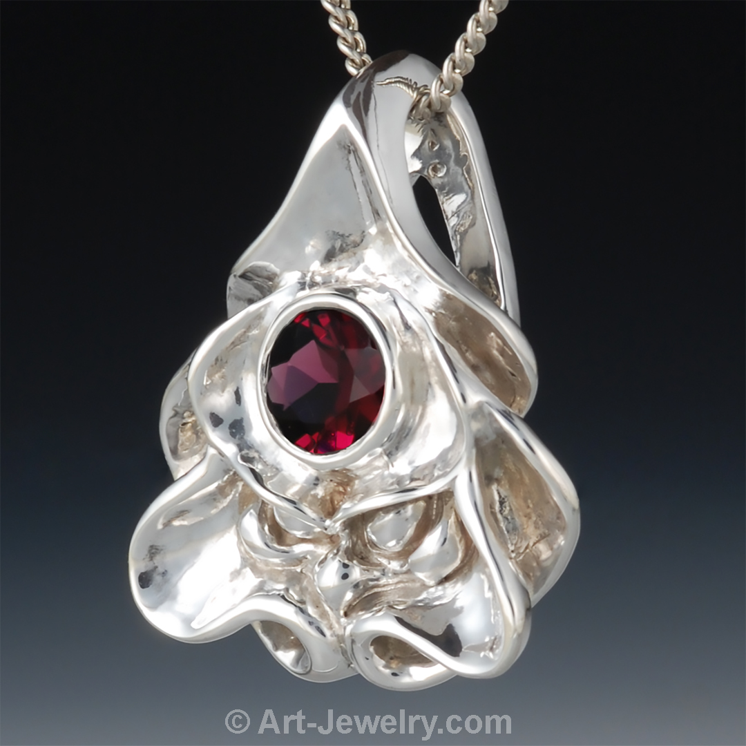 Side view of sterling silver dragon face pendant with red garnet eye