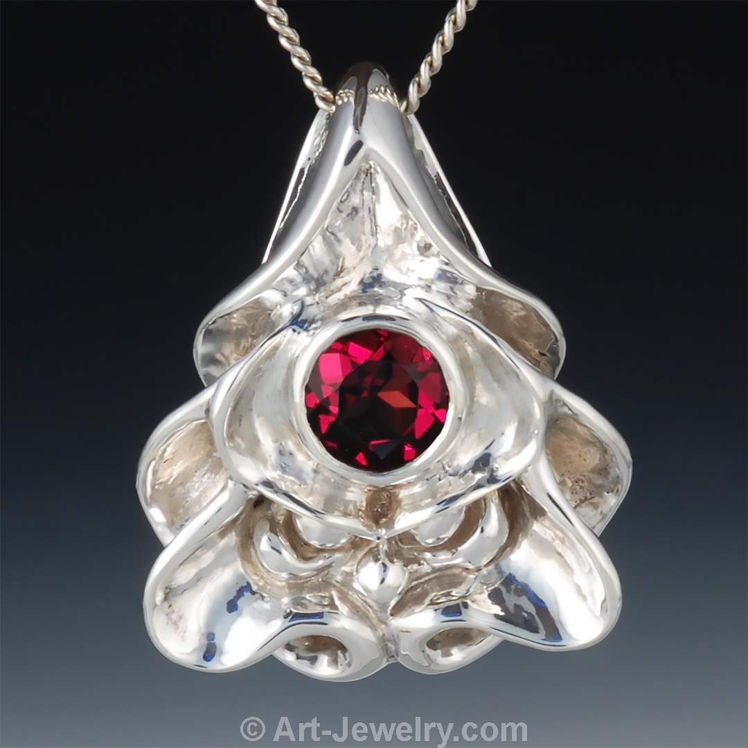 Front view of sterling silver dragon face pendant with red garnet eye