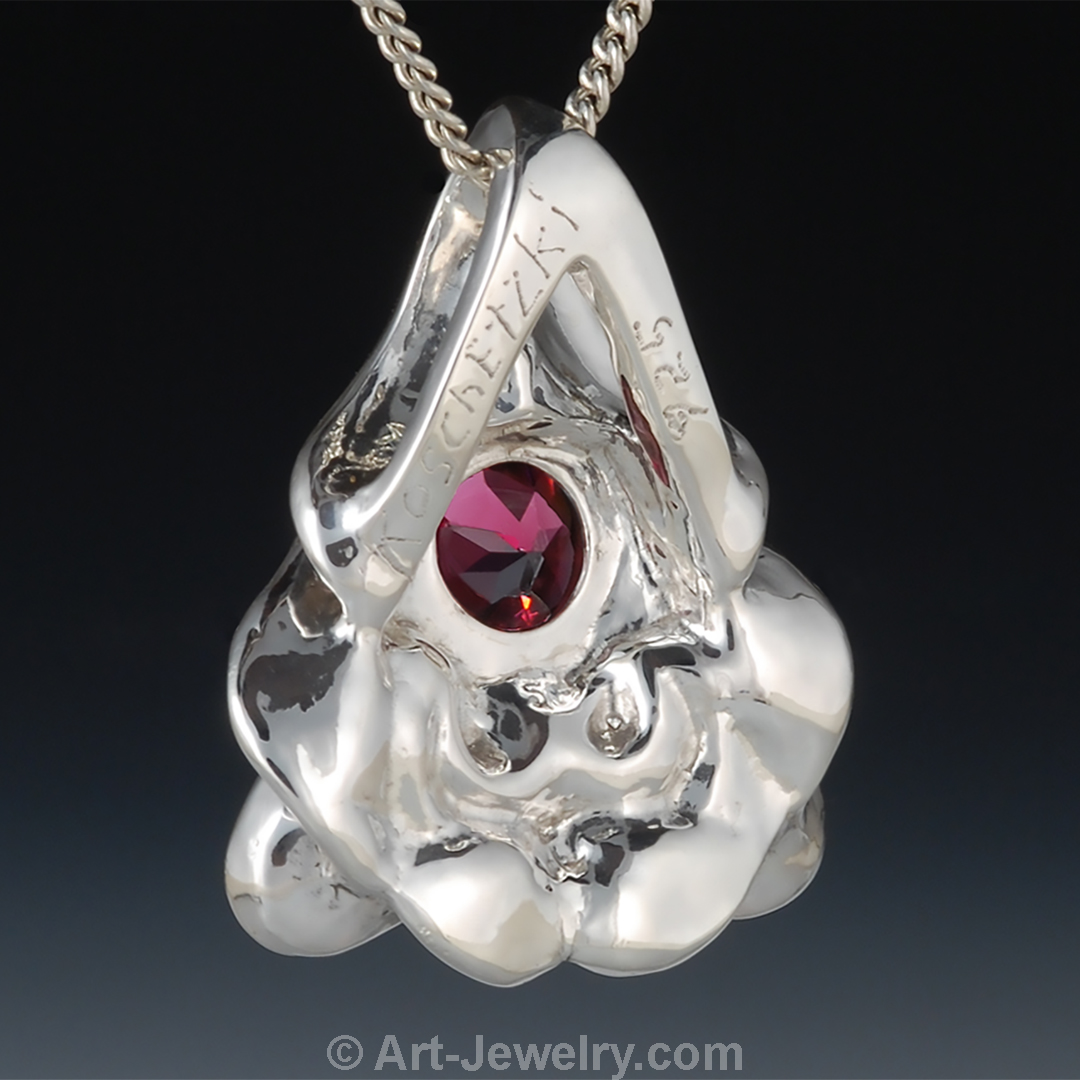Back view of sterling silver dragon face pendant with red garnet eye